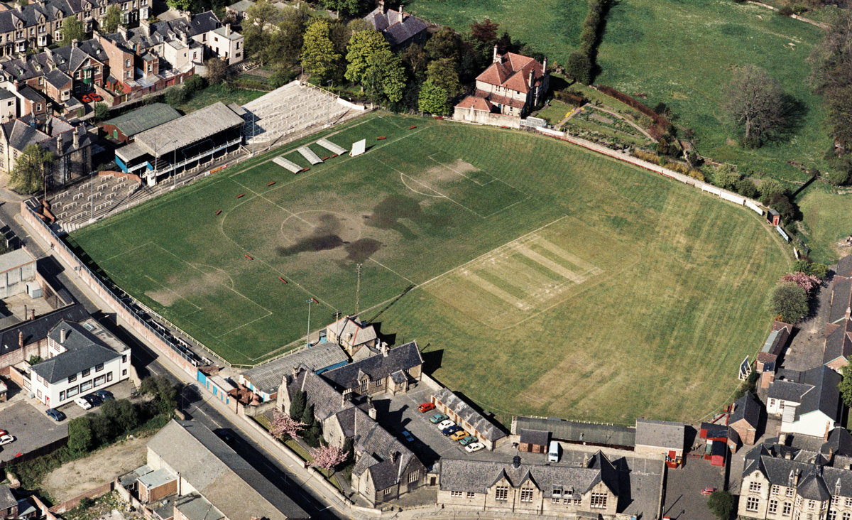 We blijven in het noorden en gaan naar Kingsway. Het oude stadion van Bishop Auckland, de meest succesvolle amateurclub van Engeland. Het werd gedeeld met de lokale cricketclub en dat is vanuit de lucht goed te zien.