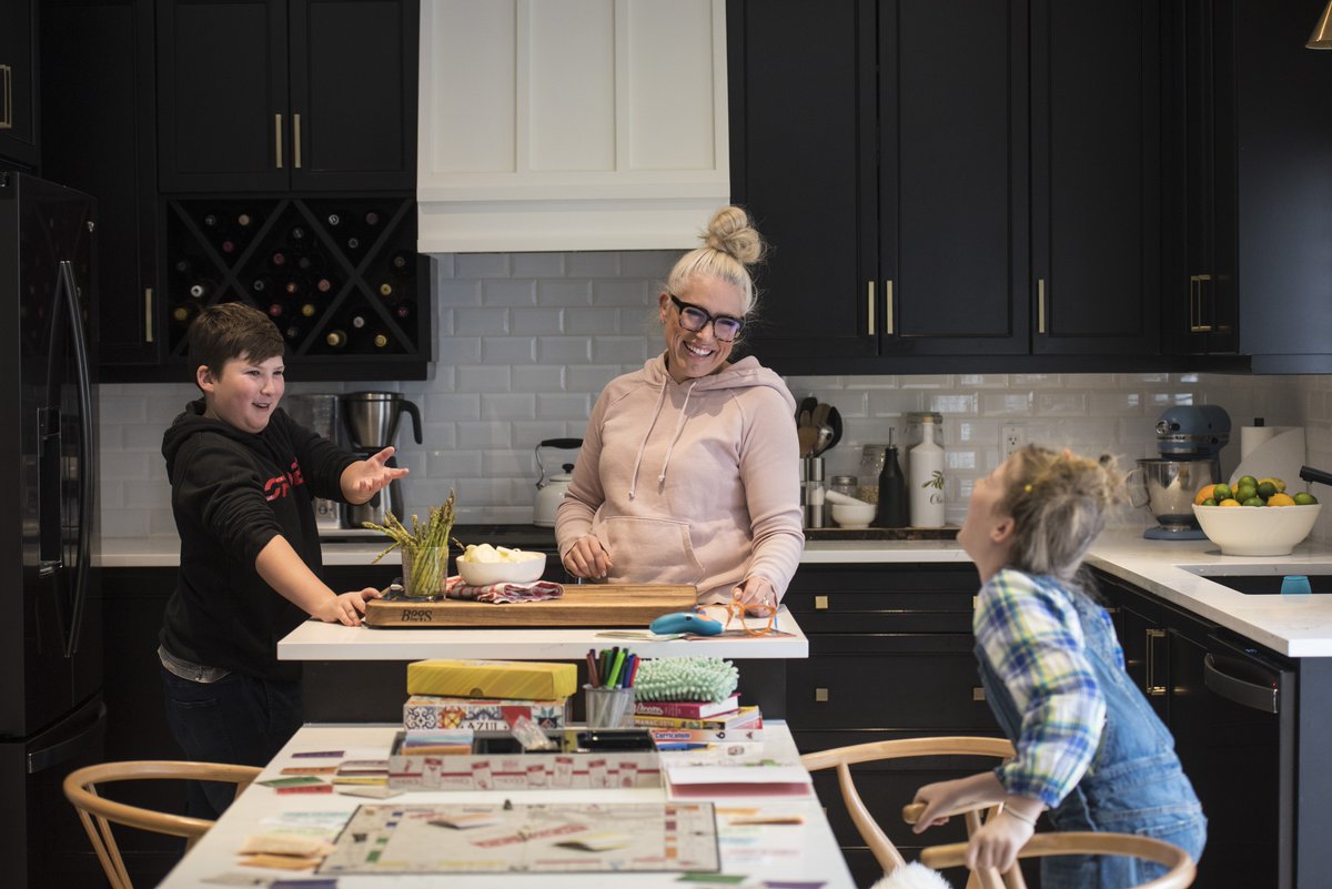  @Tijana_Martin Andrea Traynor prepares dinner as her son and daughter play monopoly at their home in Courtice, Ont., on March 17.