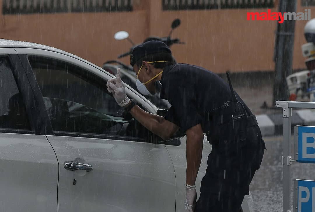 malaymail's tweet photo. Police and army personnel brave the heavy down pour as they continue manning roadblocks to ensure that the public complies with the movement control order to curb the spread of the novel coronavirus (Covid-19).

(📸: Farhan Yusoff)
#covid19 #mco #police #army #roadblock #malaysia https://t.co/UqMRK7W0Ov