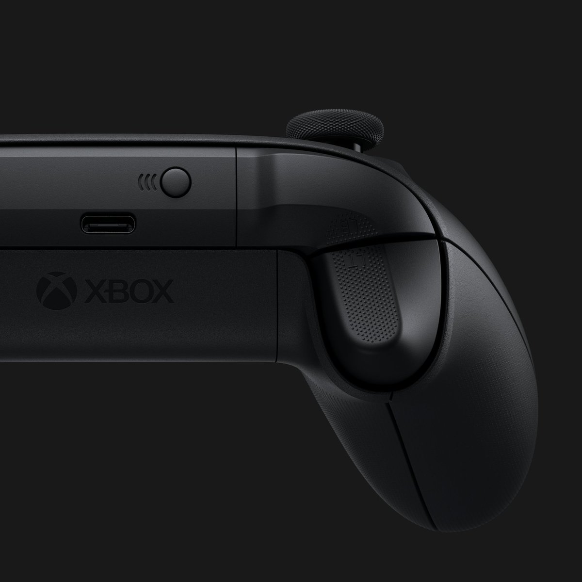 View of the top of a black Xbox controller suspended on a black background.