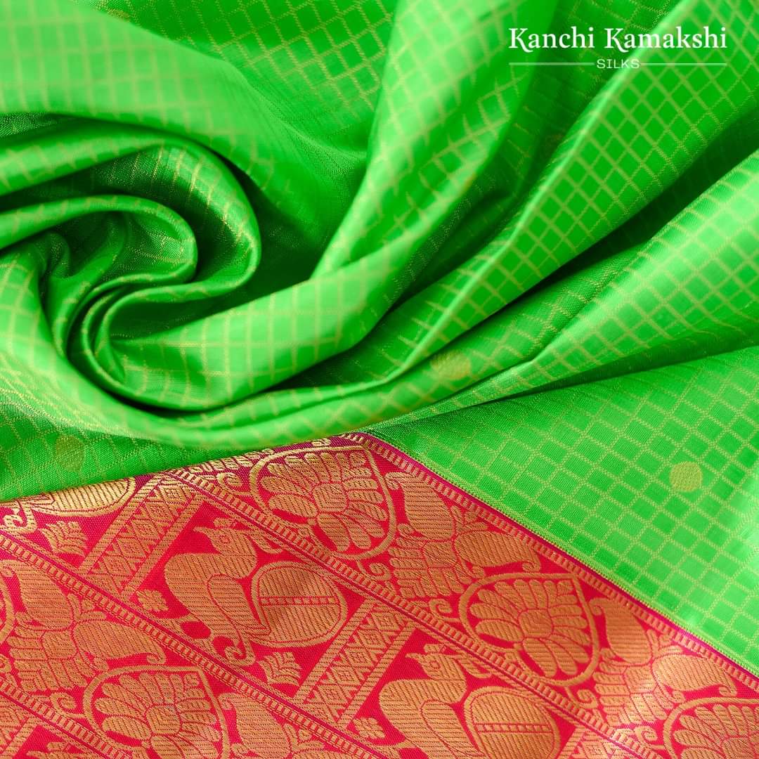 Sleek zari checks and polka dots shimmer elegantly on this Green Kanchi Silk Saree. The serene weave is given a timeless edge with a red gold zari border with floral drops, paisleys and peacock blocks.   
#Kanchisilk #Kanchikamakshisilks