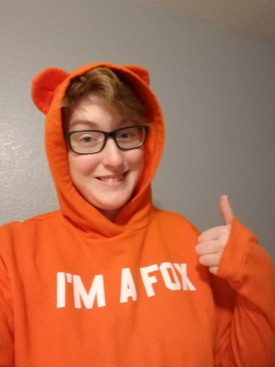 A dork in a orange hoodie with ears & "I'm a fox" printed across it, giving a thumbs up