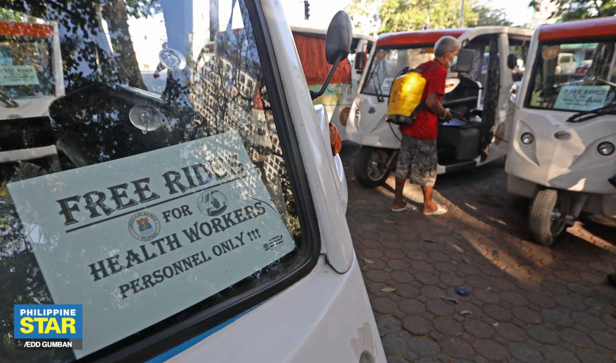 A barangay volunteer disinfects on Saturday the e-trikes parked outside the Ospital ng Maynila that will be used for the transportation of health workers in the city for free.