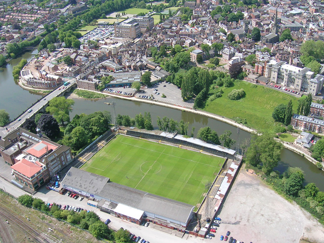 Gay Meadow van Shrewsbury Town. Helaas in 2007 gesloopt, maar gelukkig heb ik er nog een wedstrijd gezien. Heerlijk stadion en op loopafstand van het centrum. Nadeel was dat die rivier wel eens uit z'n oever trad.