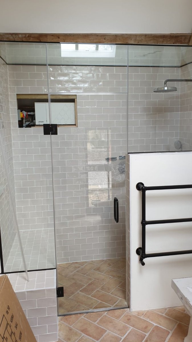 A recently fitted glass shower enclosure with a swinging door and matte black hardware for a home in Cheltenham.