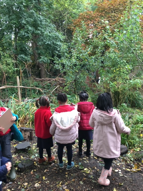 Photo shows four Year 1 children in red school uniform and winter coats, their backs to us as they look at mixed woodland beyond. Photo from Bessemer Grange Primary website http://bessemergrangeprimary.co.uk/1jm/