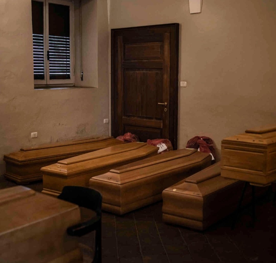 In the hospital mortuaries, coffins back up in empty rooms. The red plastic bags, filled with personal effects, mark coronavirus victims.