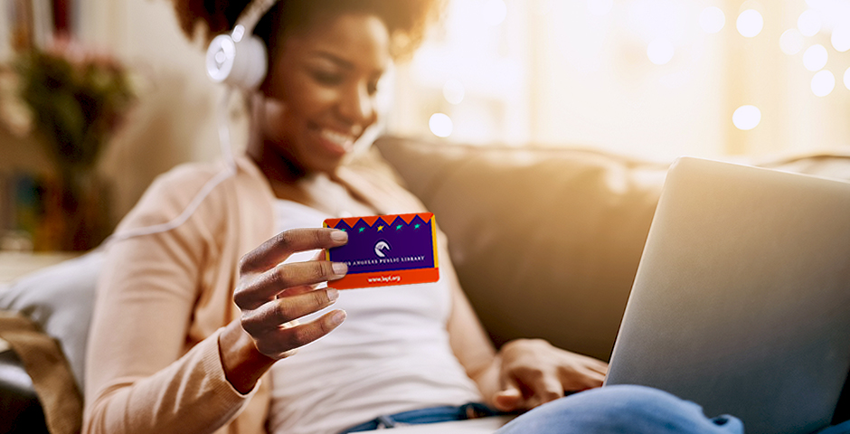 woman on her laptop holding a library card