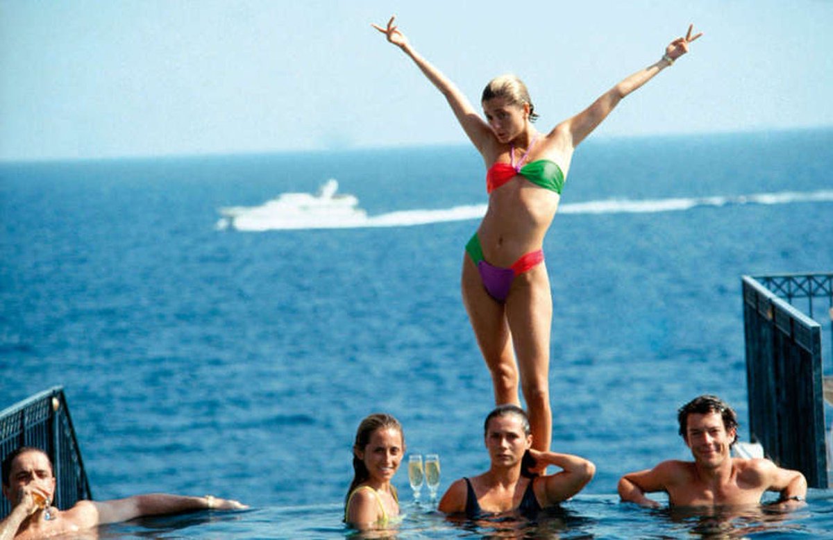 Marie Chantal Miller, future wife of Prince Pavlos of Greece, strikes an extravagant pose above her sister Pia. The group is hanging out in pool of the Hotel Belair, Cap Ferrat, France. Poolside at Lake Tahoe, California.