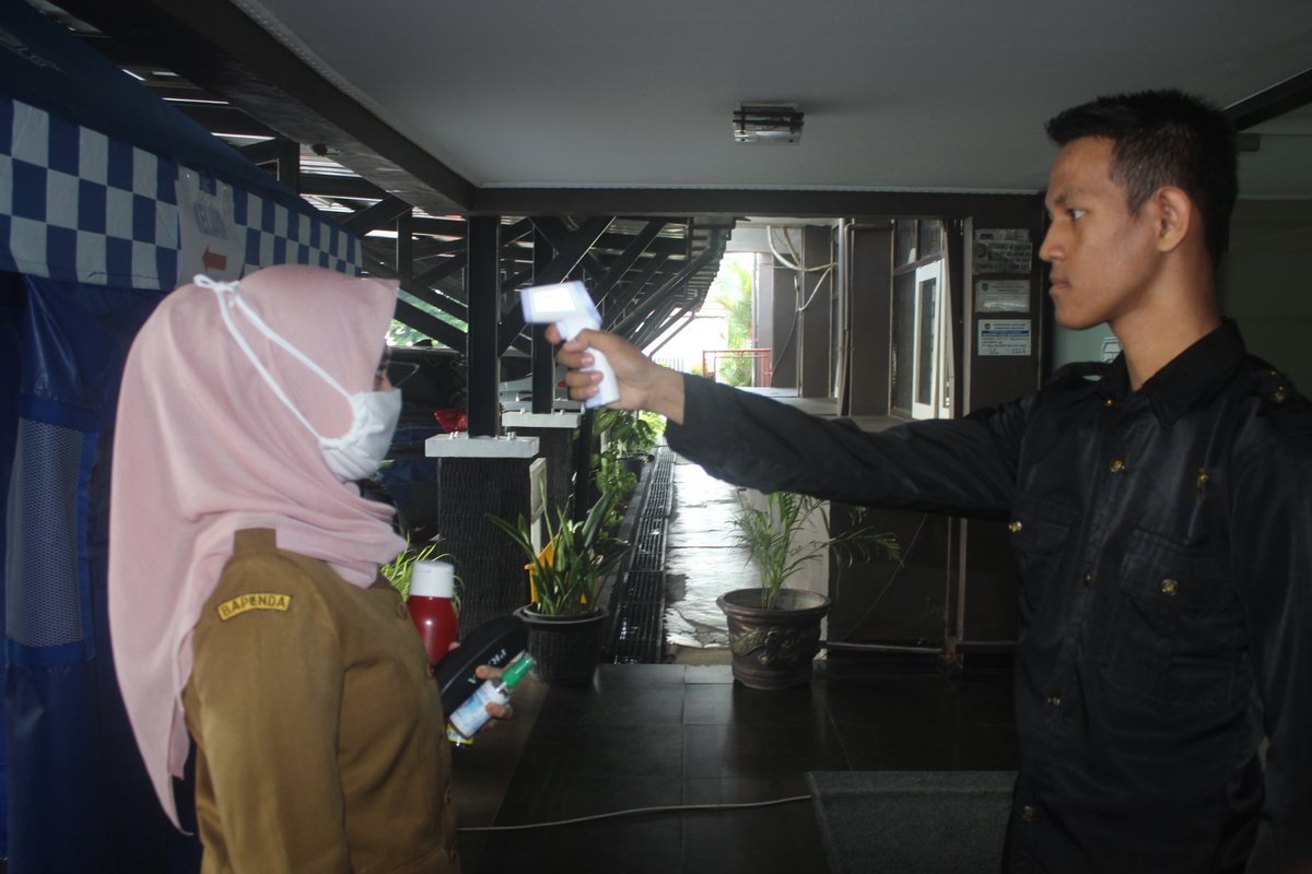 PETUGAS KEAMANAN KANTOR (SATPAM) STANDBYE DAN MENGECEK SUHU TUBUH KARYAWAN/TI DENGAN ALAT TERMO SCANNER SEBELUM MEMASUKKI RUANGAN UNTUK BEKERJA. HARI SENIN, 30 MARET 2020