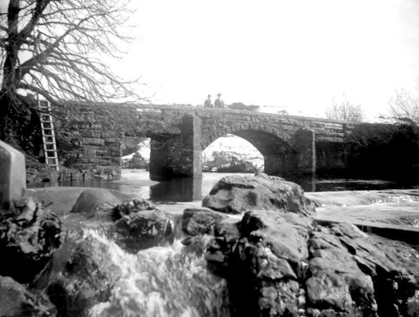dartmoorarchive's tweet photo. Hill Bridge over the River Tavy
1914
Originally a clapper bridge, later rebuilt to better transport local traffic over the #RiverTavy -it was still not considered suitable for heavy traffic. Curiously there is a ladder propped up against the left hand side of the bridge ๐๐ https://t.co/kMyOjLYKET