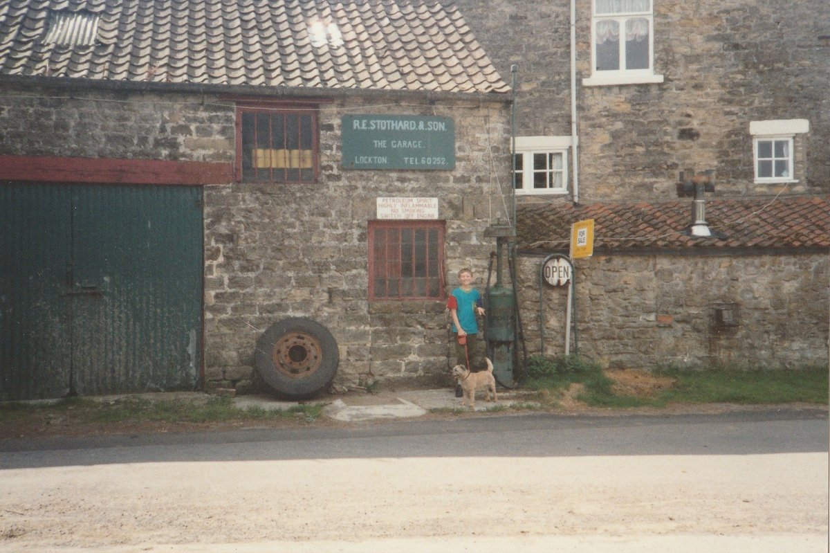 Day 100 of  #petrolstationsImperial (W. Eves)R.E. Stothard, Lockton, North Yorks, 1993  https://www.flickr.com/photos/danlockton/49721099303/A photo that means a lot to me—here I am, 11th birthday, with Bob the border terrier, in Lockton village, with a '20s Bowser pump. The garage is now  @Locktontearooms