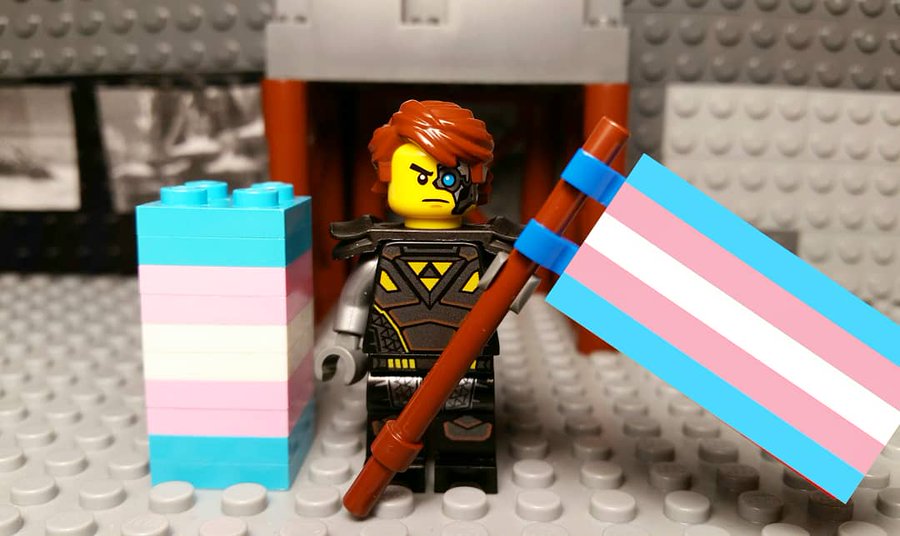 A lego character holding a transgender flag