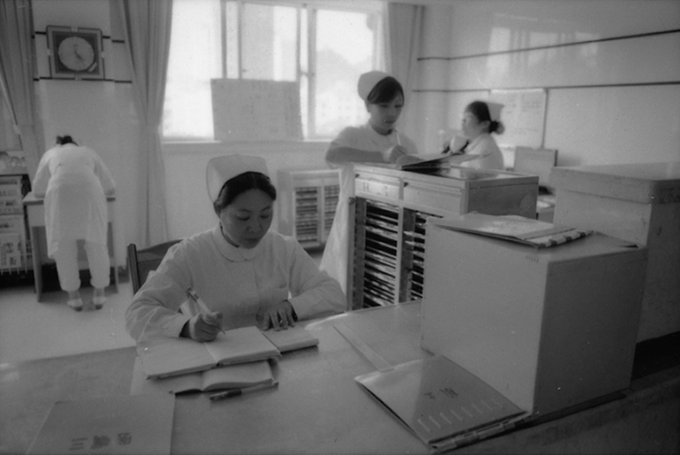 Black and white photograph of four nurses in uniforms working in a hospital in China.