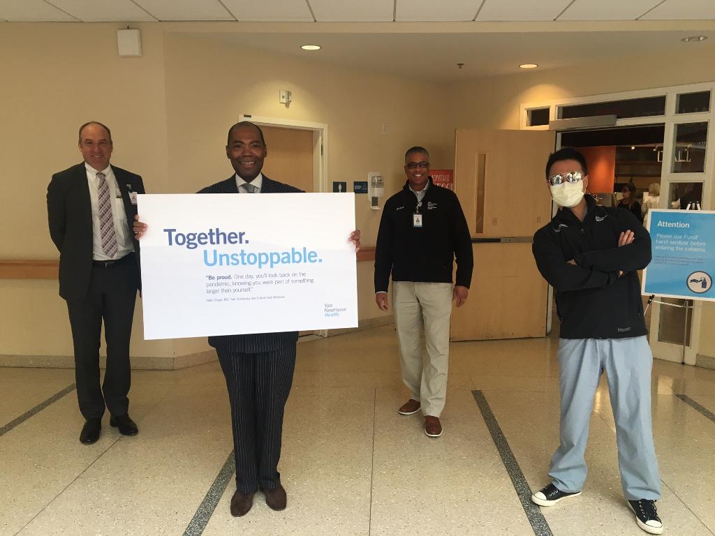ynhhealth's tweet photo. An unstoppable team – even at 6 feet apart! @TomBalcezakMD; @KChurchwellMD; @01michaelholmes &amp; Chief Quality Officer Steven Choi, MD, remind employees about social distancing and to be proud of the important, historic work they are doing to care for patients during the pandemic. https://t.co/uU56fatvt5