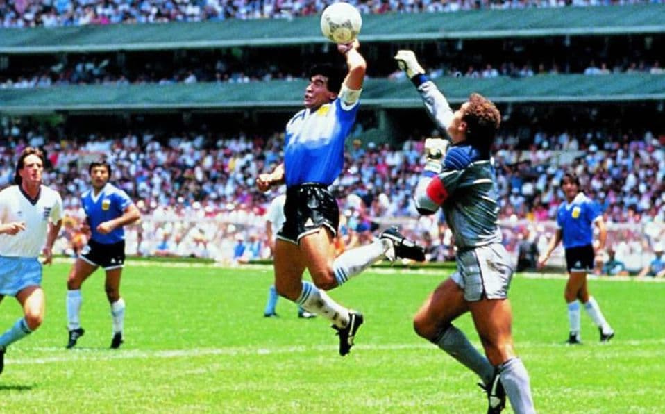 Retour en 1986.Le match est très disputé. La 1ère mi-temps, plutôt plaisante, s'achève sur un score nul et vierge.À la 51è minute survient le premier coup de théâtre: sur un ballon aérien, Maradona devance Shilton et marque de la main gauche.C'est la 'Mano de Dios'.