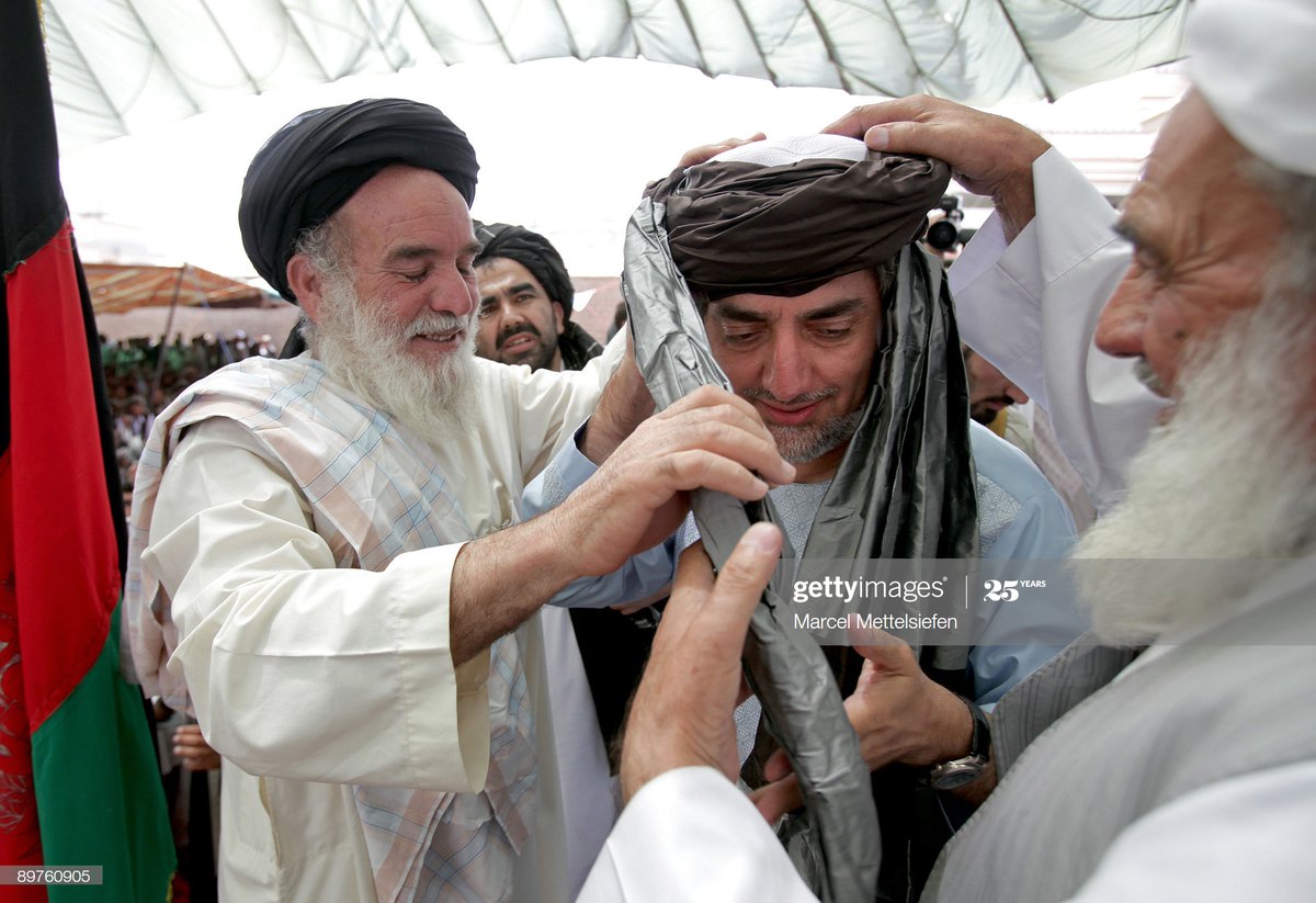 Afghan elders put a turban on the head of Abdullah Abdullah.