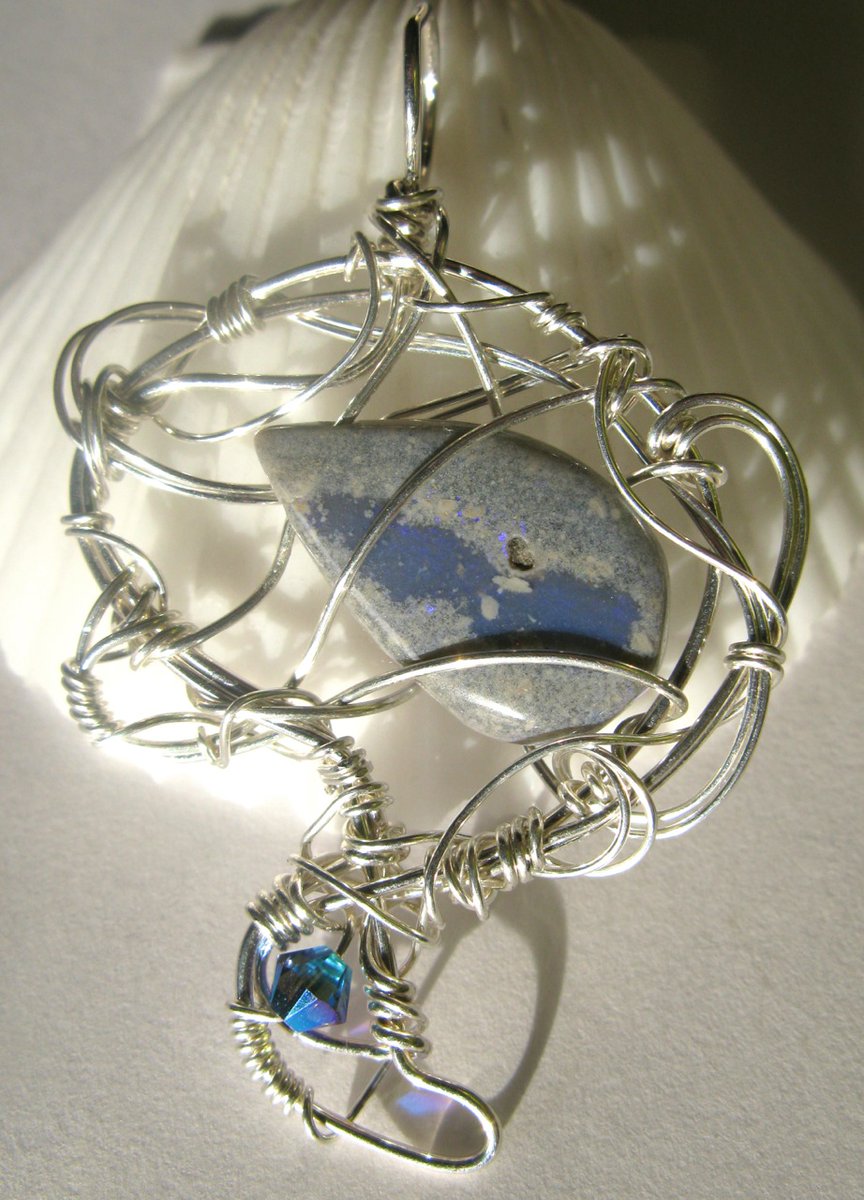 "Interstellar Landscape Architects' Open House" is a sterling silver wirework pendant with one opal and one Swarovski crystal.