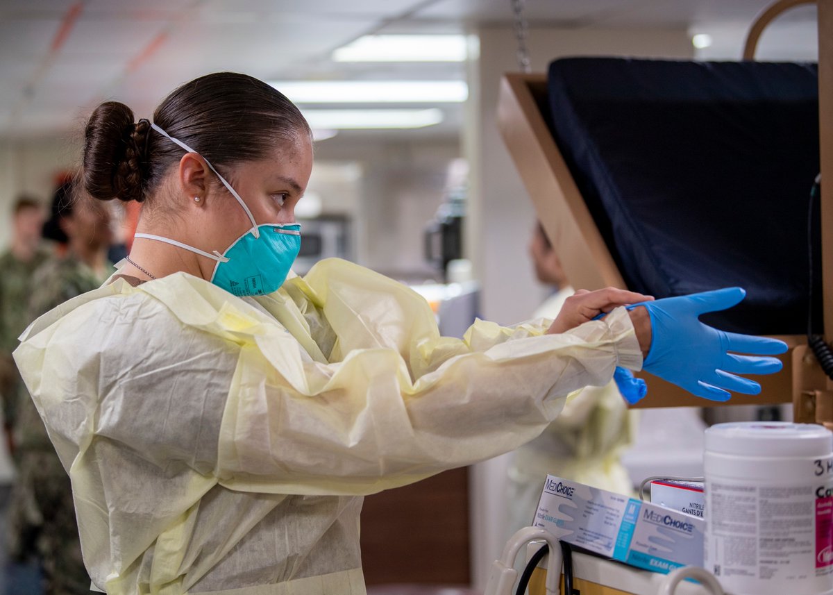 04/03/20  http://WWW.DFNS.TV Hospitalman Melissa Montes, from Stockton, Calif., dons surgical gloves prior to treating patients aboard the hospital ship USNS Mercy (T-AH 19) April 3. Mercy will serve as a referral hospital for non-COVID-19 patients.