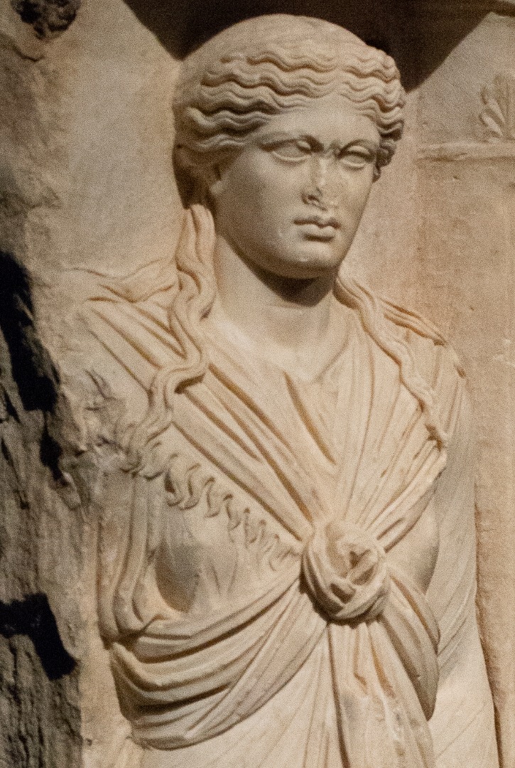 Marble Gravestone of Alexandra, Athenian priestess of Isis shown in the guise of the goddess. Her dress' central knot is characteristic of Isis cult devotees. Also her 2 ritual objects: situla [ritual bucket] & sistrum (rattle, now missing) AD 125-150, Kerameikos Cemetery, Athens