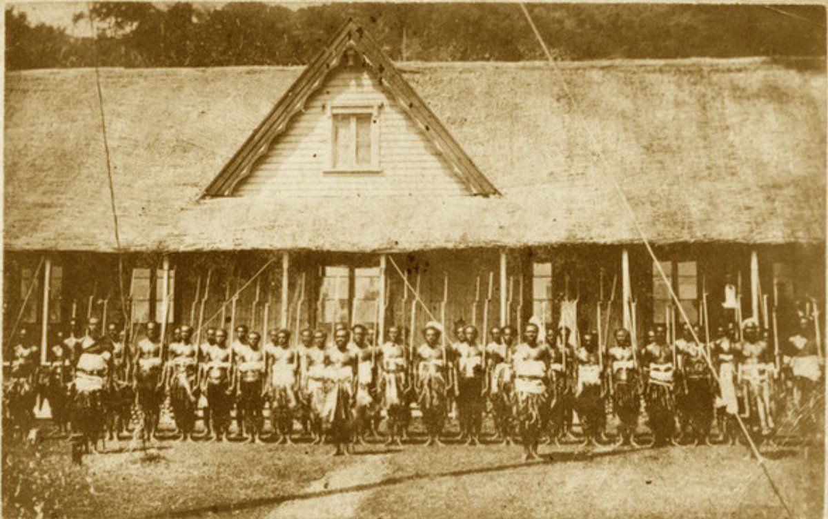 Fijian soldiers on parade wearing traditional dress and carrying firearms. Photographed by F H Dufty in Nasova, Levuka, Fiji, in the 1870s or 1880s