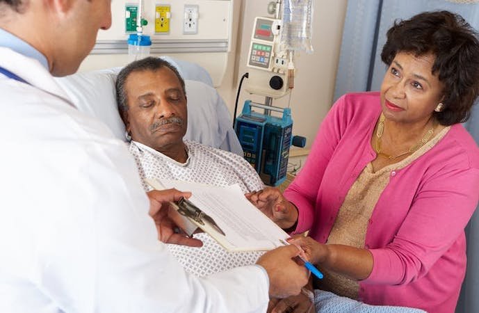 Stock photo of man in hospital bed, with doctor and family member