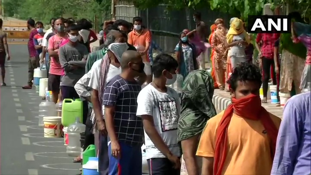 ANI's tweet photo. Delhi: People in Chilla village line up to collect drinking water from Delhi Jal Board (DJB) trucks, amid #CoronaLockdown. They says, "we have to queue up for at least 2-3 hours to collect drinking water due to shortage of water. The water tanker comes only once in 3-4 days". https://t.co/jRo5XpJ01S