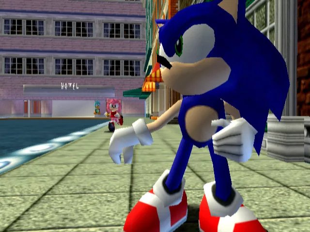 SA1Facts's tweet photo. According to a Dreamcast 1999 presskit showing multiple early screenshots of the development of Sonic Adventure, there was originally a sign on the building for the hotel entrance, likely to recognize it easier; this was later scrapped in all published versions of the game. https://t.co/I18JKT1NQ2