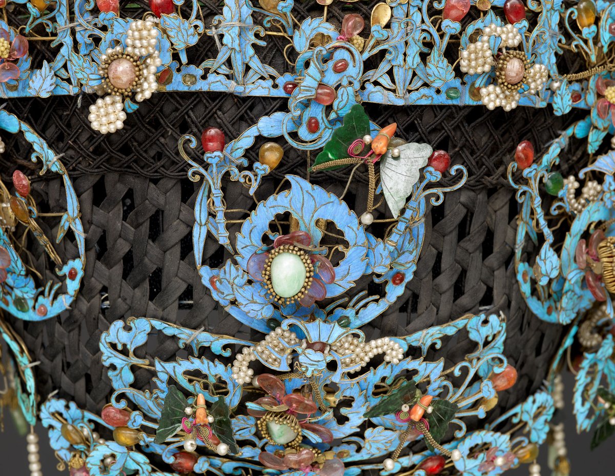 The decoration consists of gemstones, pearls, coral & enamel work representing flowers leaves & butterflies. The blue colour comes from inlaid kingfisher feathers which during the Qing dynasty, were used exclusively by the imperial court & wealthy families …https://storiesfromthemuseumfloor.wordpress.com/2018/06/15/the-chinese-manchu-headdress/