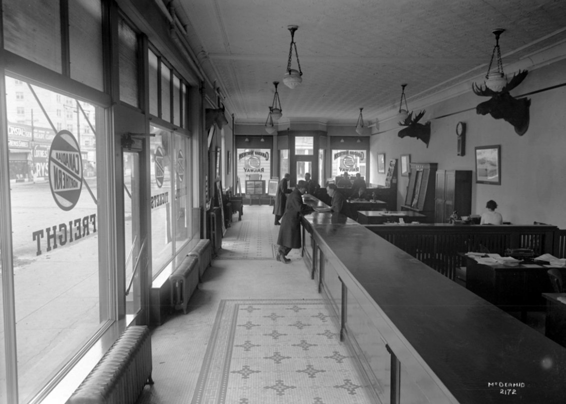 No longer a tobacco store, Canadian National Railway ticket office would operate out of the corner retail space. Here's an interior view looking south. (100th street on the left)• NC-6-2172 (1916)