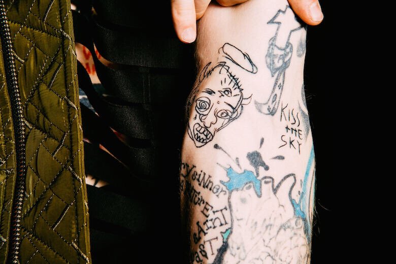 𝗞𝗶𝘀𝘀 𝘁𝗵𝗲 𝗦𝗸𝘆: this is a song from his 2017 album “bloom.” he said the song represents a sense of nirvana for him. the face tattooed next to it is artwork from his friend Mod Sun
