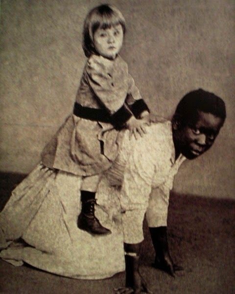54 - Uma criança negra serve de "cavalinho" para uma criança branca nos tempos de escravidão no Brasil, no final do século 19.