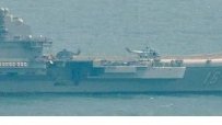 Most prominently showing in the formation is the aircraft carrier Liaoning (16), China's first. The Kuznetsov class ship has six aircraft visible on deck (3 fighters and 3 helicopters). At least one (and probably 3) J-11/J-15 is identifiable, with 2 helos probably Z-18s.