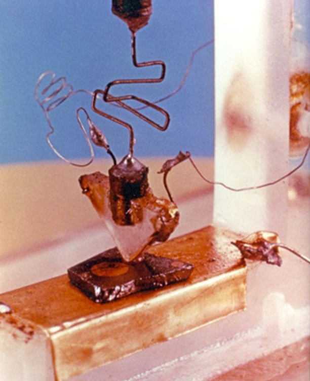 here's a photo of the first bipolar transistor. the semiconductor is a tiny sliver of germanium resting on a metal base. (yes, this is where the base terminal gets its name.)