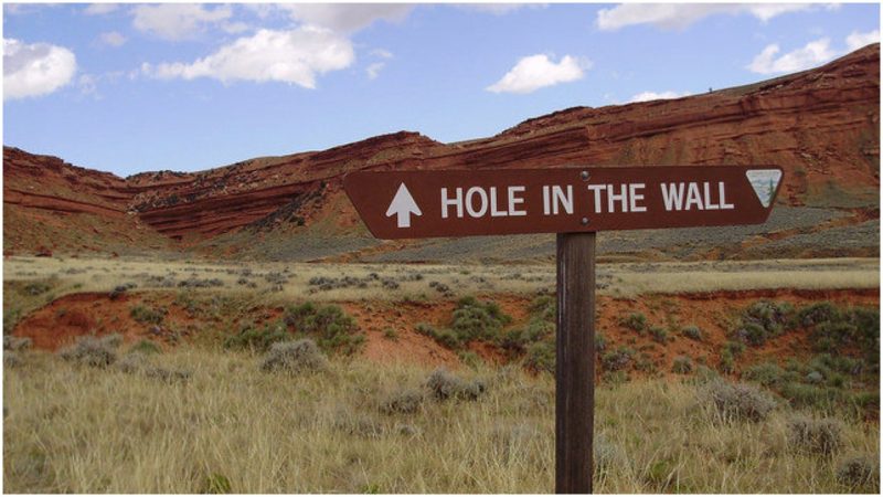 The Hole in the Wall is a real place, up north of Casper. Outlaws who used it included Butch Cassidy and the Wild Bunch and Jesse James. It was remote and easily defended due to narrow entry. I assume the signage wasn't quite like this back then