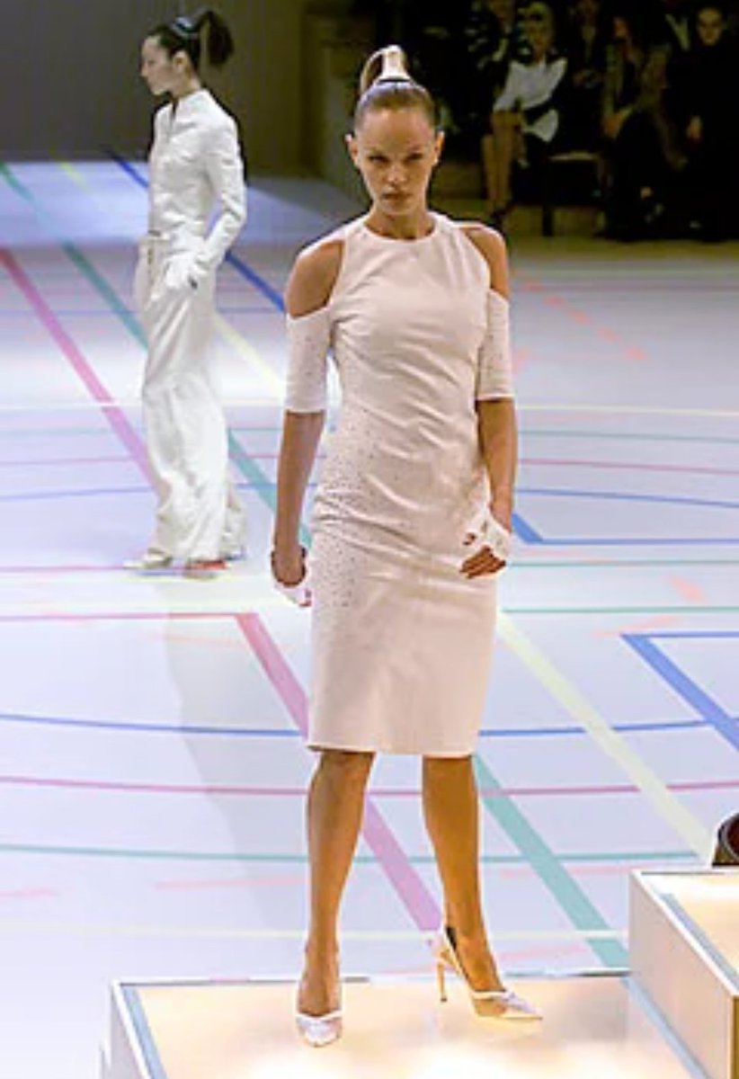 Givenchy SS 2000:Cette collection est présentée dans un décor imitant un gymnase et les mannequins défilent sur des podiums.