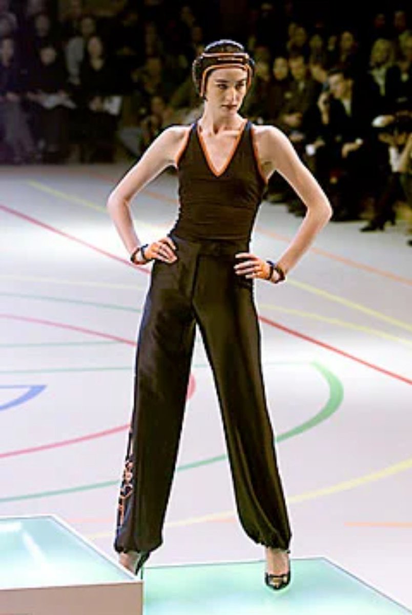 Givenchy SS 2000:Cette collection est présentée dans un décor imitant un gymnase et les mannequins défilent sur des podiums.