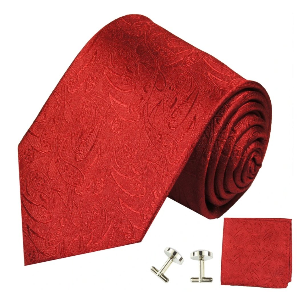 Around his collar is a red, paisley tie that looks to be made of some kind of silk, he swirling pattern matching wonderfully with the mask on his face, as well as the red cufflinks he can see pinned to his wrists of the same pattern.