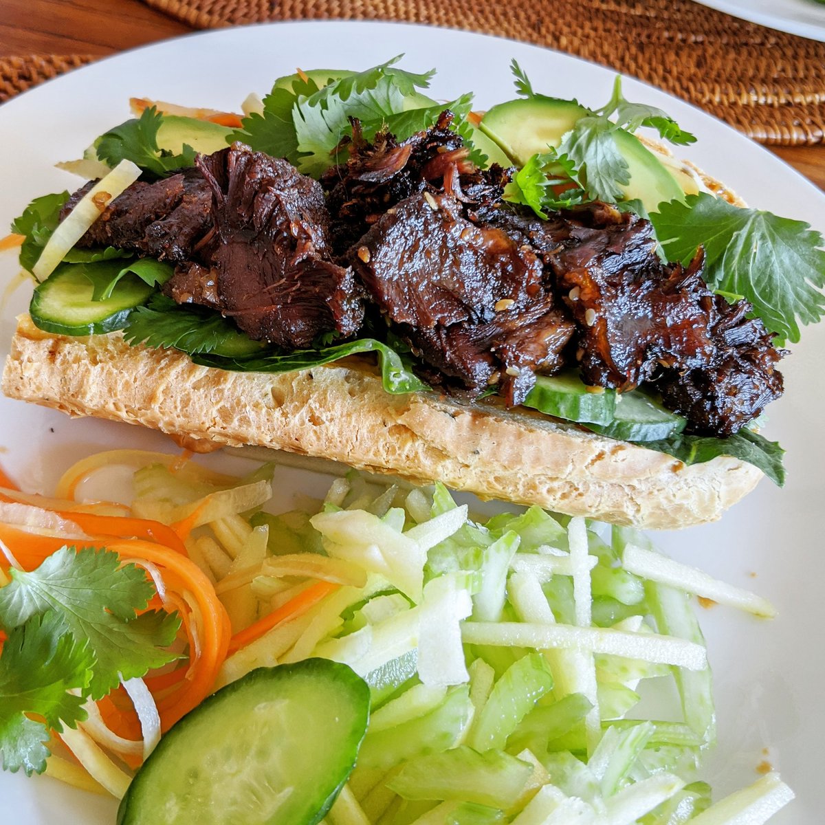 Short rib banh mi with pickled rainbow carrots, cucumbers, cilantro, shishito peppers, Sriracha aioli, romaine and avocado in a tapioca baguette. Served with celery and apple salad. 