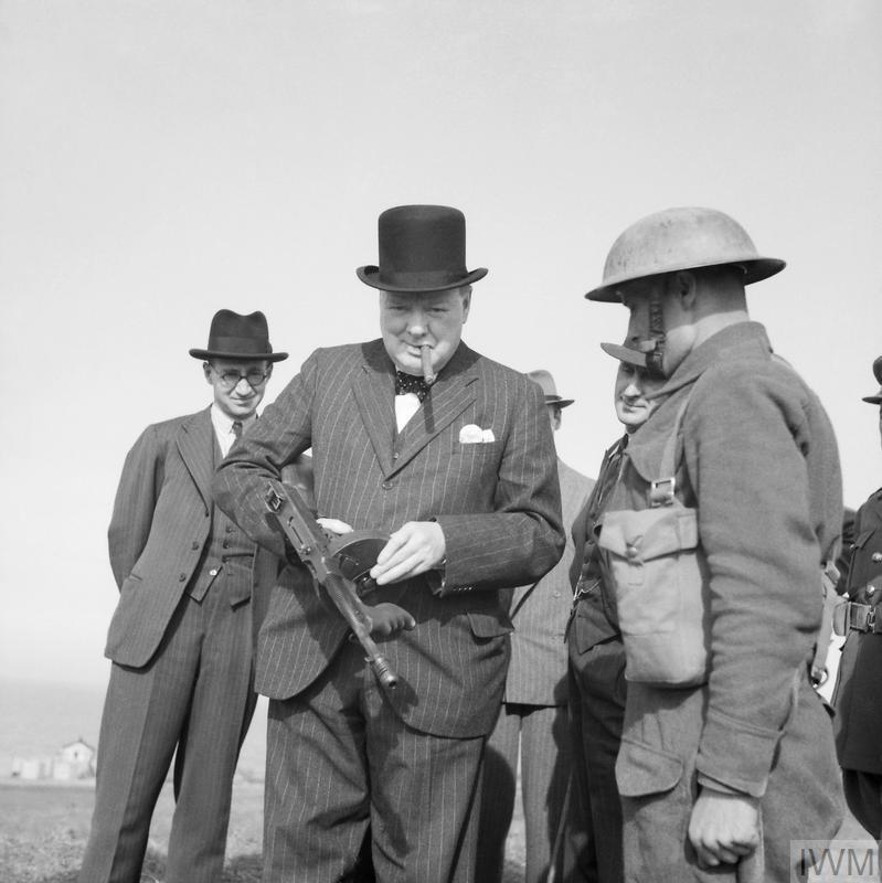 This was not Churchill's 1st encounter with a Tommy Gun, being photo'd with one in July 1940, while inspecting coastal defences. Famously popular with American gangsters, the gun had a pugnacious image that Churchill was happy to use himself.© IWM H 2646 https://www.iwm.org.uk/collections/item/object/205197236