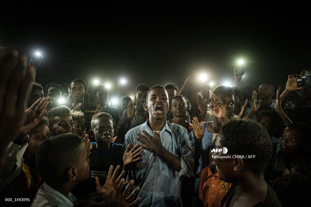 AFPphoto's tweet photo. Huge congrats to @YasuyoschiChiba who wins ‘World Press Photo of the Year’ award for his photo of a young man reciting protest poetry while demonstrators chant slogans calling for civilian rule in Khartoum, Sudan #AFP #WPPh2020 @WorldPressPhoto https://t.co/Rx4hm3hPqc https://t.co/y1LIkU46mz
