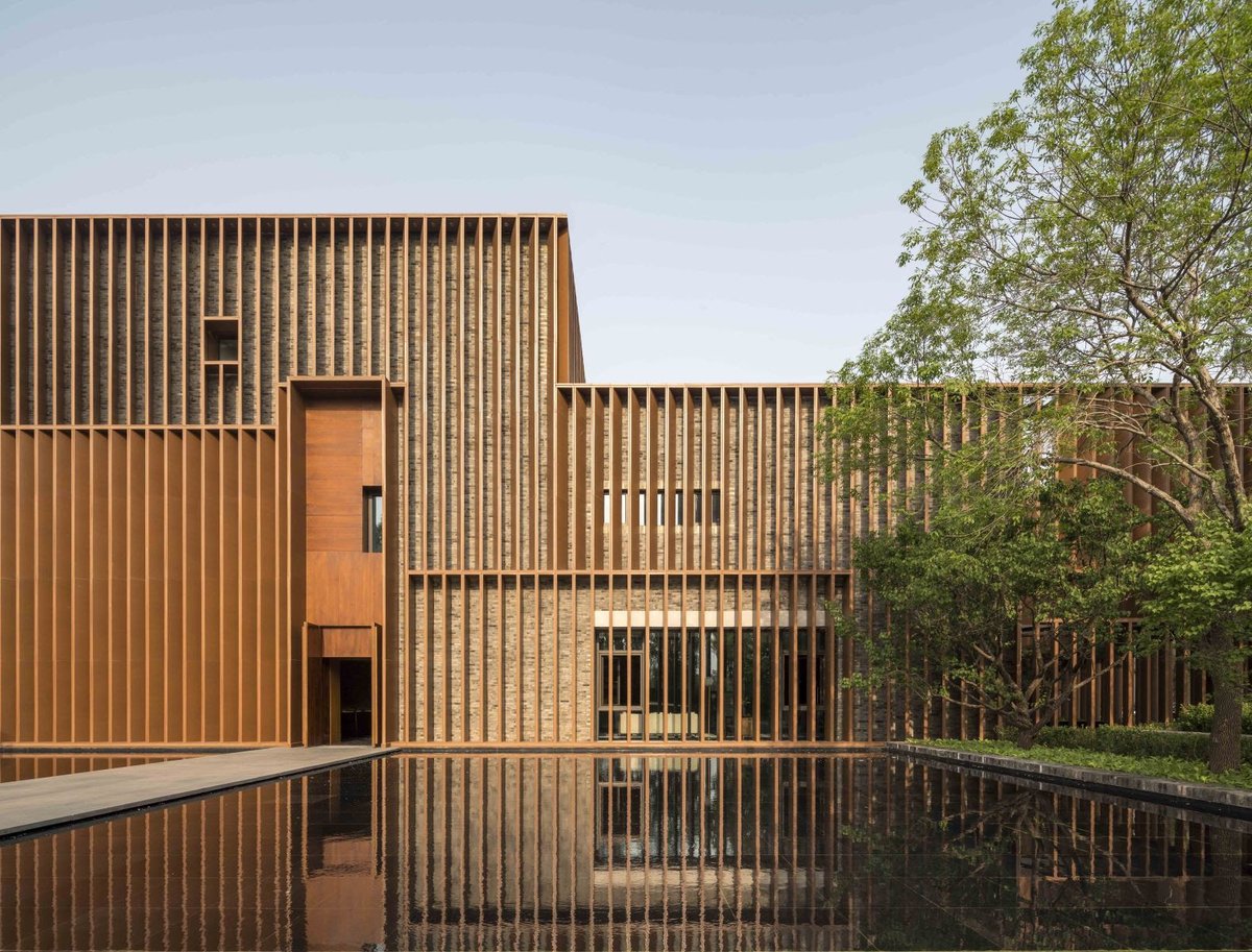 On the façade, warm-toned wood pattern aluminum grilles form a veil that softens the heaviness of the brick facade. Interior spaces can be easily caught in sight, rendering each facet of the outer wall a different visual effect.