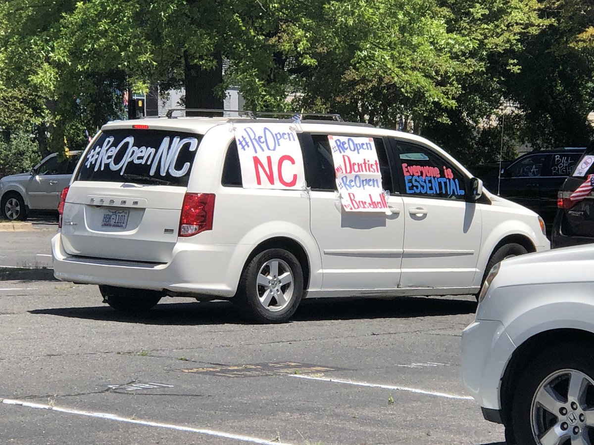Brett_Jensen's tweet photo. The local protest group #ReopenMeck has started its 2-hour drive in a loop in uptown with dozens of cars carrying flags and blowing their horns. @wbtradio #StayConnectedTogether https://t.co/9OSBwWOeKg