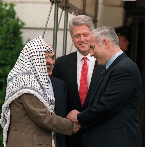 Now, on September 29, 1998, Yasir Arafat to the right of President Bill Clinton. To his left is Israeli PM Netanyahu.Just a few years earlier he used to appear with this very menacing look around him, with a gun appearing menacing from his belt.