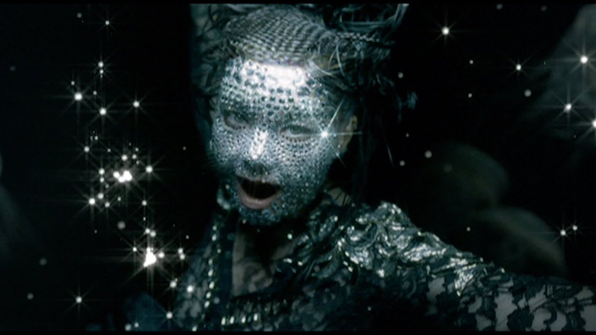 Oceania (2004)Björk is depicted as "Mother Oceania", with her face adorned by crystals. Camera pans down to darker, deeper waters. Björk appears out of the dark background, singing and covered with sparkling jewels. Images of jellyfish swim around carried by the currents