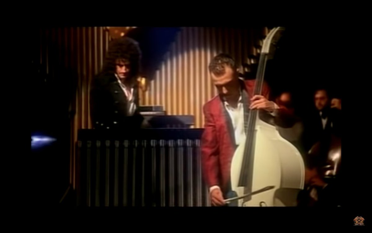 The video also features bass guitarist John Deacon playing a white double bass, despite not performing on the original recording.