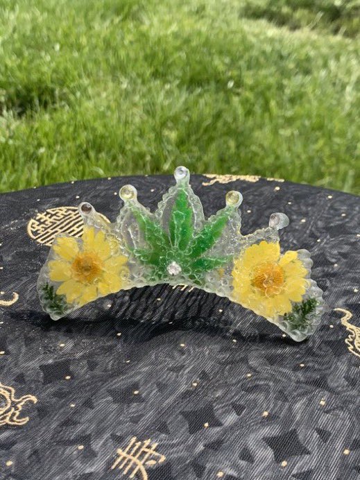  @reagannsandberg my name is Reagan and I’m a baby resin and jewelry artist located in Kansas! My @ is  @reagannsandberg and I just made a resin tiara with a pressed weed lookin leaf, some yellow daisies, and rhinestones :)