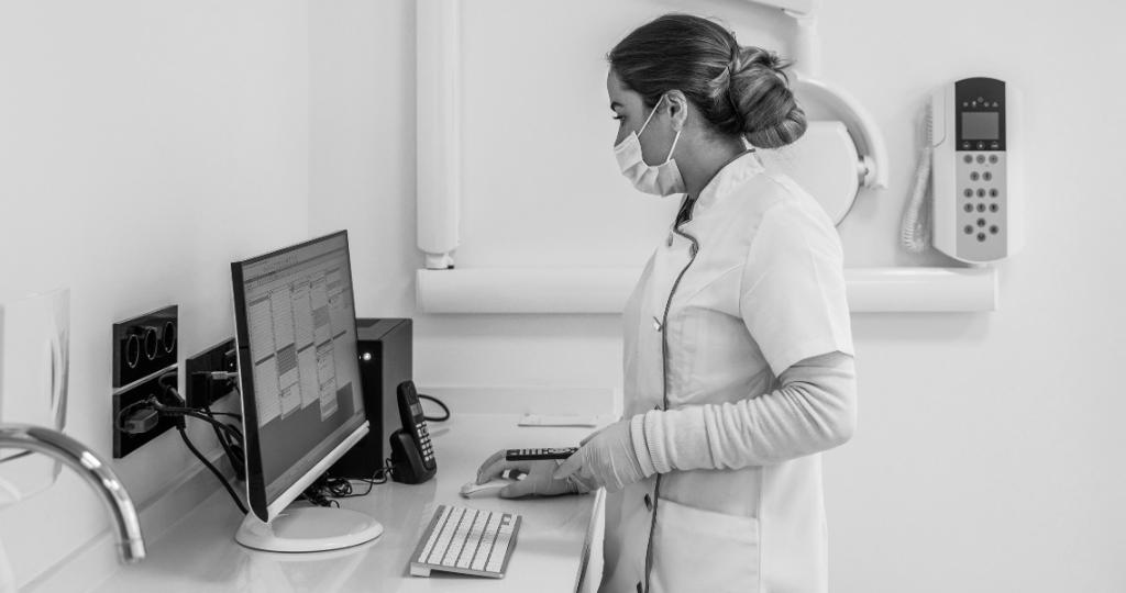 masked female clinician at computer
