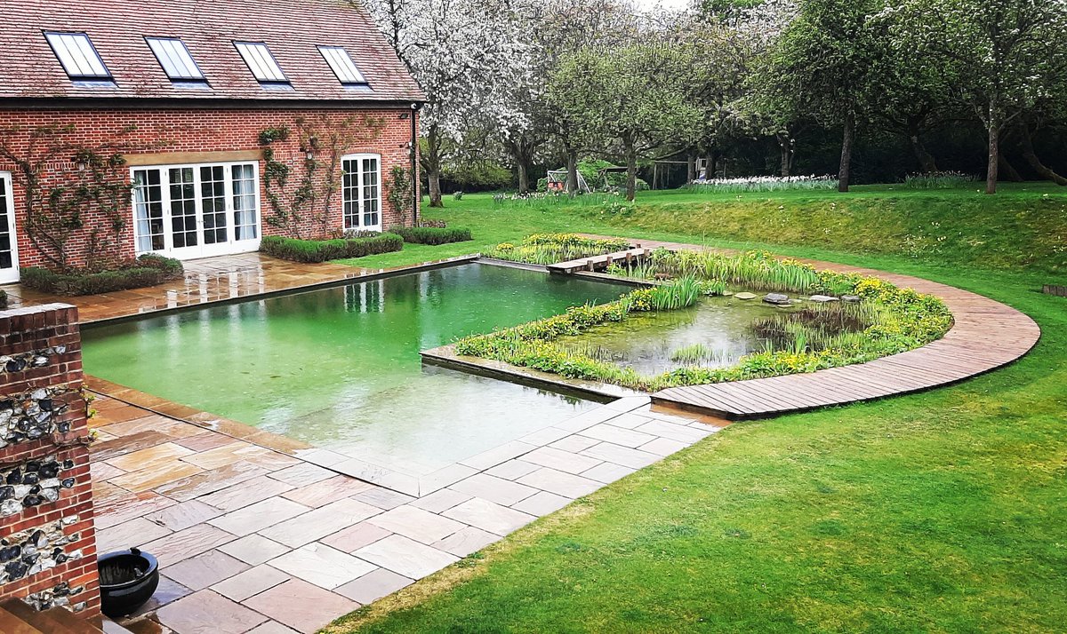 Built in 2011, this beautiful natural swimming ponds filtration and swim zones are separated and heated. The air temperature is 13°C but the swimming pond water is 27°C! 💚
#gardendesign #biodiversity 
#naturalswimmingpond #clearwater #chemicalfreepools #swimmingponds #pond