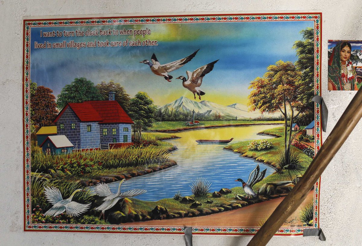 In the family's hut, a poster hangs on the wall. It depicts a red-roofed house on a lake, sun setting behind snow-capped mountains. A pair of mallard ducks fly overhead.“I want to turn the clock back to when people lived in small villages and took care of each other,” it says.